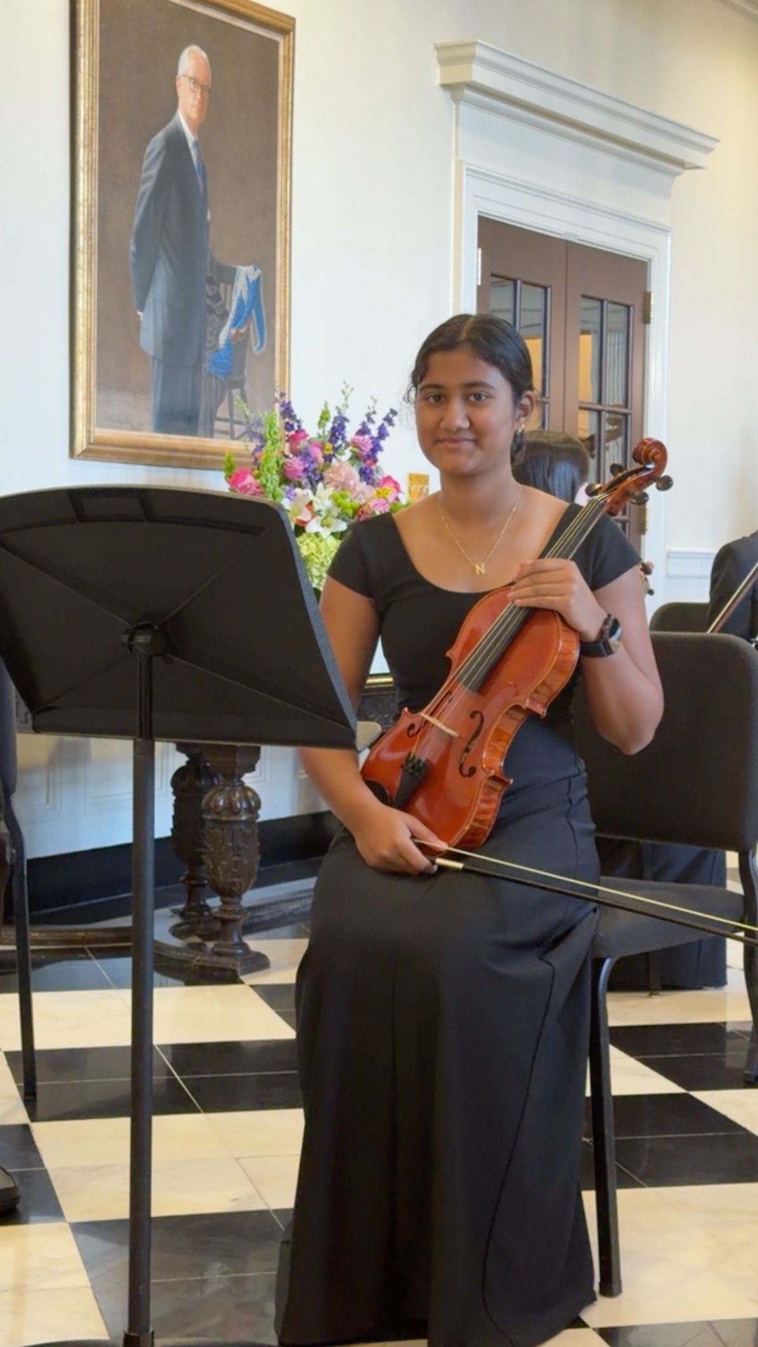 Navya seated with her violin in concert black